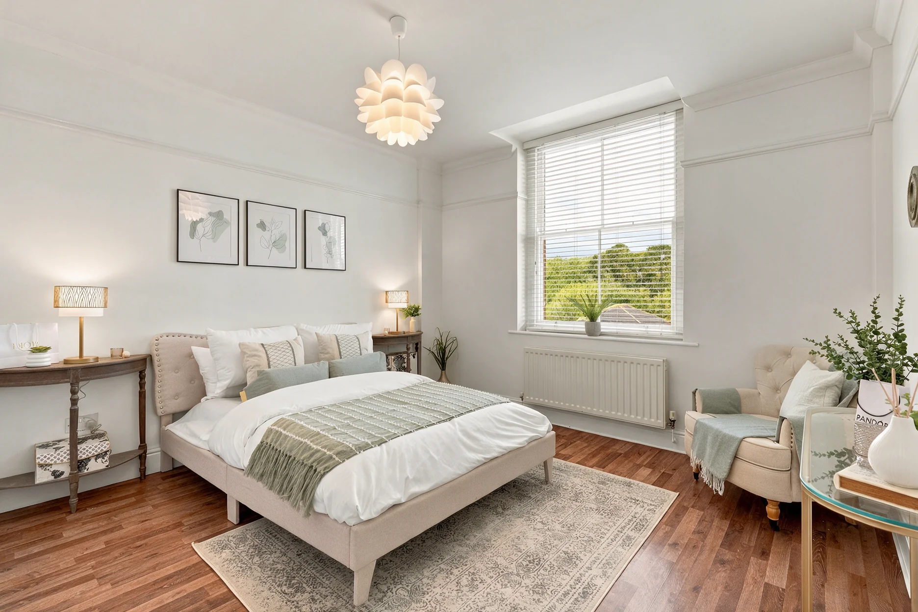 Staged bedroom at Barrington Grange with green accents, an armchair and a pendant light