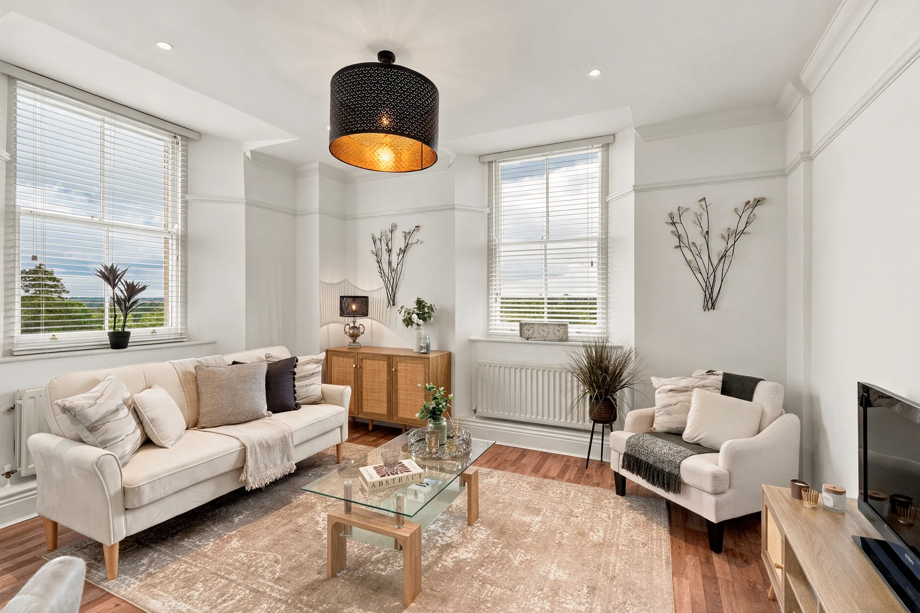 Staged living room at Barrington Grange with a sofa, armchair and glass coffee table
